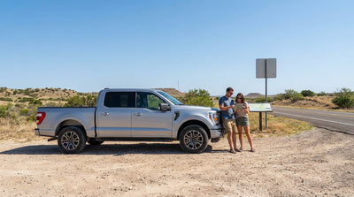 A car rental SUV drives down a dusty off-road trail through the rugged Texas landscape at golden hour