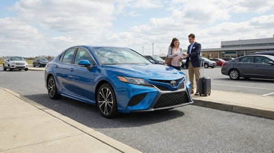 A silver car hire vehicle drives on a winding road through the rolling hills of Pennsylvania