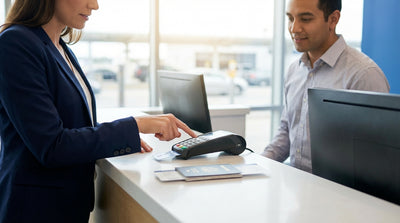 A traveler uses a credit card to pay for their car hire at an airport counter in the United States