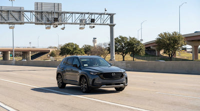 A modern car rental driving under an electronic toll gantry on a sunny multi-lane highway in Texas