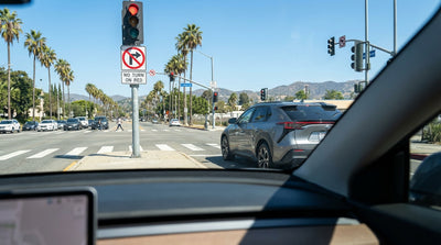 A car hire stopped at a red light on a sunny Los Angeles boulevard lined with palm trees