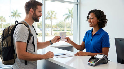 A convertible car rental driving down a sunny coastal road lined with palm trees in Florida