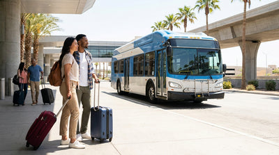 Traveler walking with luggage past overhead signs for car rental services at the Las Vegas airport
