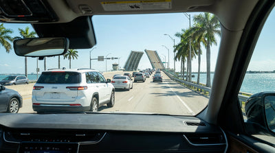 Driving a car hire across a sunny Miami causeway with a drawbridge and the city skyline in the distance