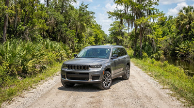 A white car hire on a dirt road traveling through the wild, green wetlands of the Florida Everglades