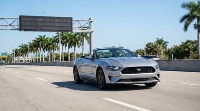 A car rental approaches an electronic toll gantry on a sunny multi-lane highway in Miami