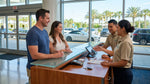 A person's hands holding car keys and a rental agreement at a car hire desk in Orlando