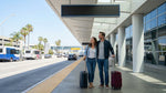 A car rental shuttle picking up travelers with luggage outside Terminal 8 at LAX airport in Los Angeles