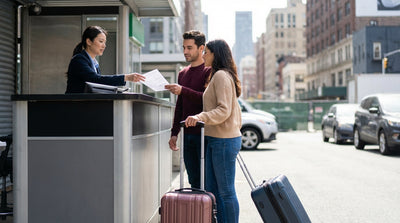 A traveler with luggage waits for an off-airport car rental shuttle bus in New York