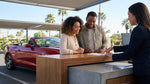Couple in a convertible car rental driving along the scenic coast of California