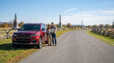 A car hire drives on a paved road through the grassy fields and monuments of Gettysburg, Pennsylvania