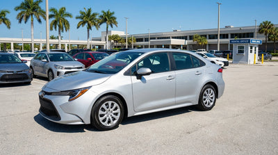 A young driver smiles beside their convertible car hire on a sunny, palm-lined road in Florida