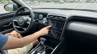 Close-up of a driver's hand touching the dashboard screen of a car rental vehicle in Orlando