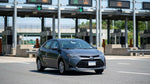 Silver car rental passing through an electronic toll plaza on a New York highway