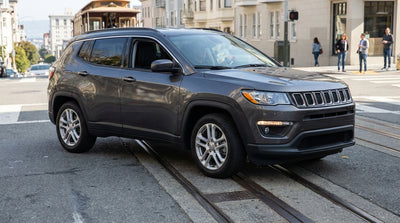 A car hire vehicle crosses tram tracks on a sunny, sloped street in San Francisco