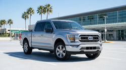 A white SUV car rental driving on a straight desert highway in Texas under a clear blue sky