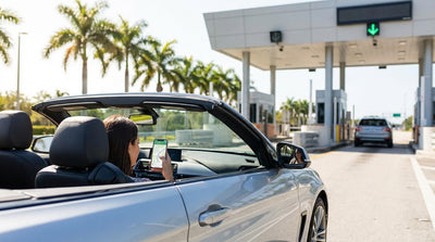 A car rental driving under an electronic toll gantry on a sunny highway in Florida