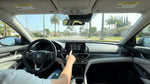 Close-up of a driver adjusting dashboard controls inside a car rental parked on a sunny street in California