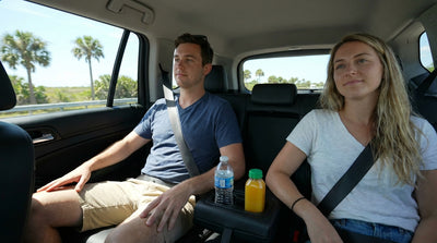 A convertible car hire driving down a scenic, palm-lined coastal road in sunny Florida