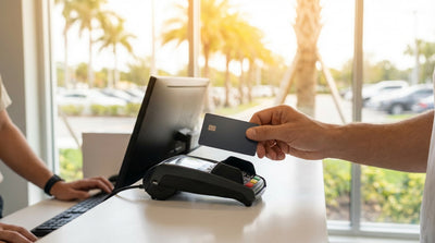 A customer hands a credit card to an agent at a car rental counter in a sunny Florida airport