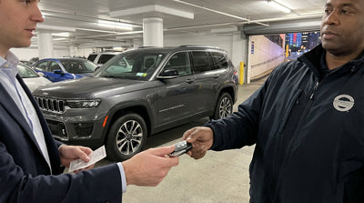 A valet takes the keys to a car rental in a busy New York parking garage