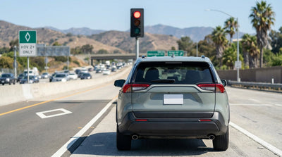 A car hire drives in the HOV lane on a sunny California freeway lined with palm trees