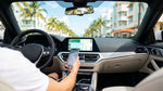 Driver plugging a smartphone into a dashboard USB port inside a car rental in Miami