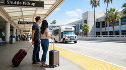 A car hire shuttle bus picking up passengers with luggage at the curbside of Terminal 8 in Los Angeles