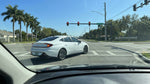A driver in their car hire waits at a red light on a sunny, palm-lined street in Orlando