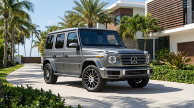 A sleek Mercedes G-Wagon car rental parked on a sunny, palm-lined street in Miami's South Beach
