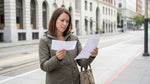 Person holding paperwork next to a car hire vehicle parked on a San Francisco street