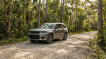 A white SUV car hire on a gravel road through the lush, green Everglades landscape on a sunny day near Miami