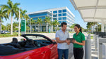 A modern car rental driving across a bridge toward the downtown Miami skyline under a clear blue sky