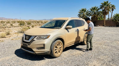 A dusty white car rental on a desert road near Las Vegas, set against dramatic red rock formations