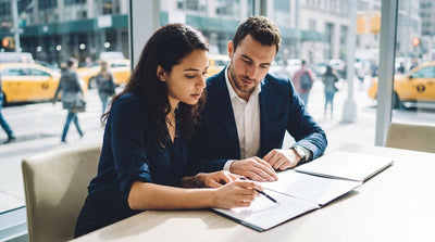 A person at a car rental desk in New York City carefully reviewing the agreement before signing
