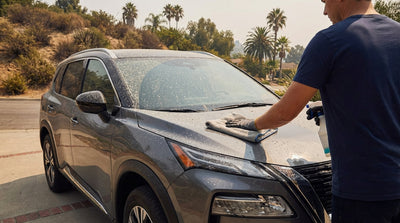 A dark car hire in Los Angeles with its hood and windshield covered in a layer of grey wildfire ash