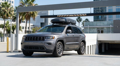A white car hire SUV with a roof rack drives down a sunny, palm-tree-lined street in Los Angeles