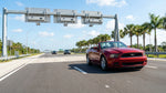 A car rental driving down a sunny, palm tree-lined highway in Florida