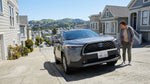 A car hire carefully navigates down a steep San Francisco street lined with colorful Victorian houses