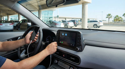 A driver connecting their phone to a car rental dashboard to use Android Auto in Los Angeles