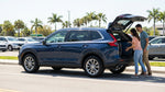 White intermediate SUV car rental driving past green palm trees on a sunny Florida coastal highway