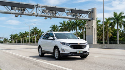 A white car hire vehicle driving on a sunny multi-lane highway in Florida lined with palm trees