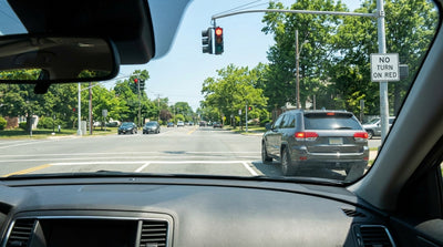 A rental car stopped at a red traffic light at an intersection on a street in upstate New York