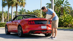 Person inspecting the rear license plate and registration tag on a car rental in Florida