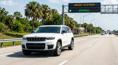 A silver sedan car hire driving on a sunny highway in Orlando lined with lush green palm trees
