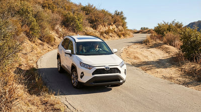 A car hire navigates a tight curve on a winding canyon road in the hills above Los Angeles