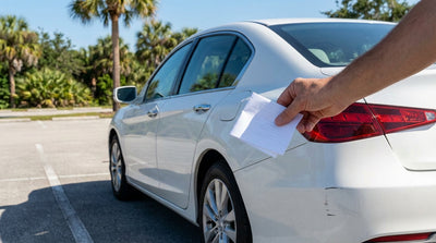 A driver inspects a minor scrape between their car hire and another vehicle in a sunny Florida parking lot