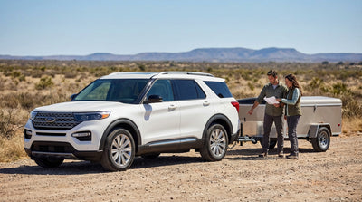 A pickup truck car rental towing a small trailer along a wide open highway in the Texas landscape
