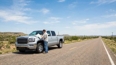 A silver car rental driving down a long, empty highway under a big sky in the Texas desert landscape