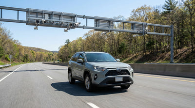 A hire car driving on the Pennsylvania Turnpike towards a modern cashless toll gantry